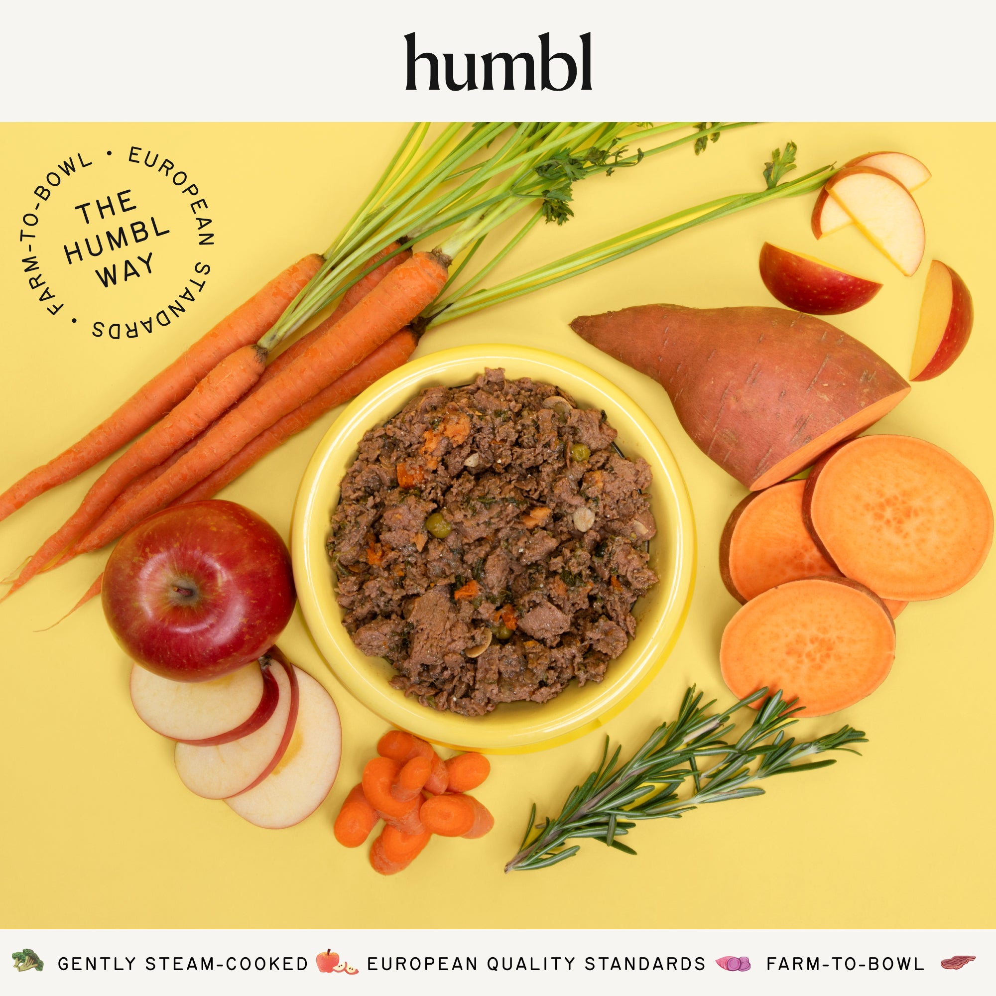 Bowl of humbl Country Chicken gently cooked dog food surrounded by fresh carrots, sweet potato, apple, and rosemary